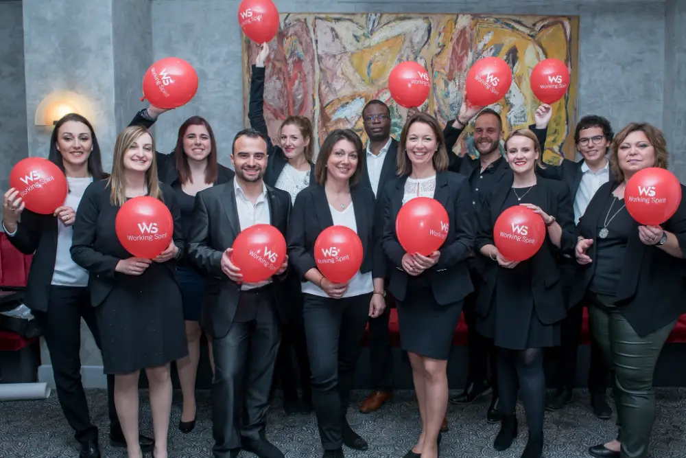 Équipe d'entreprise souriante tenant des ballons lors d’un événement professionnel