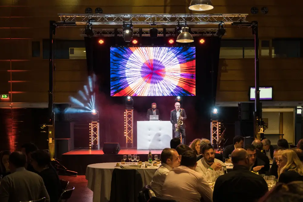 DJ et saxophoniste animent une soirée avec des jeux de lumière pendant un dîner de congrès.
