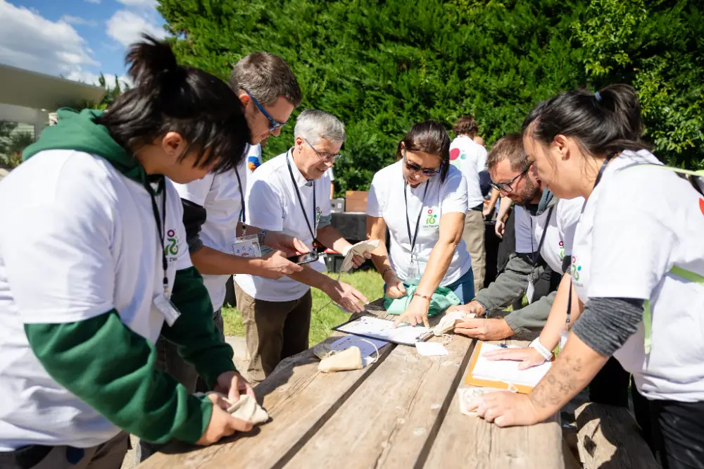 telier de team building en plein air, avec des participants réunis autour d'une table en bois pour résoudre une énigme.
