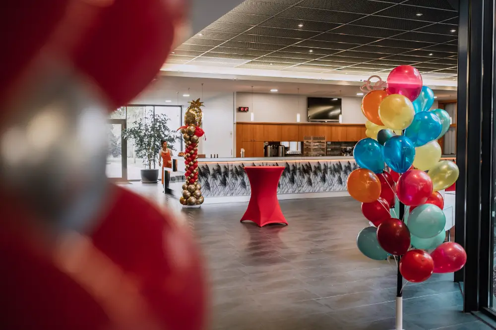 Décoration d’entrée d’un événement avec arche de ballons multicolores et mobilier de réception moderne dans un hall spacieux