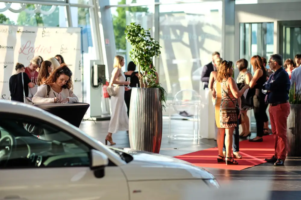 Cocktail de networking dans un showroom automobile avec tapis rouge et branding événementiel, organisé par une agence spécialisée