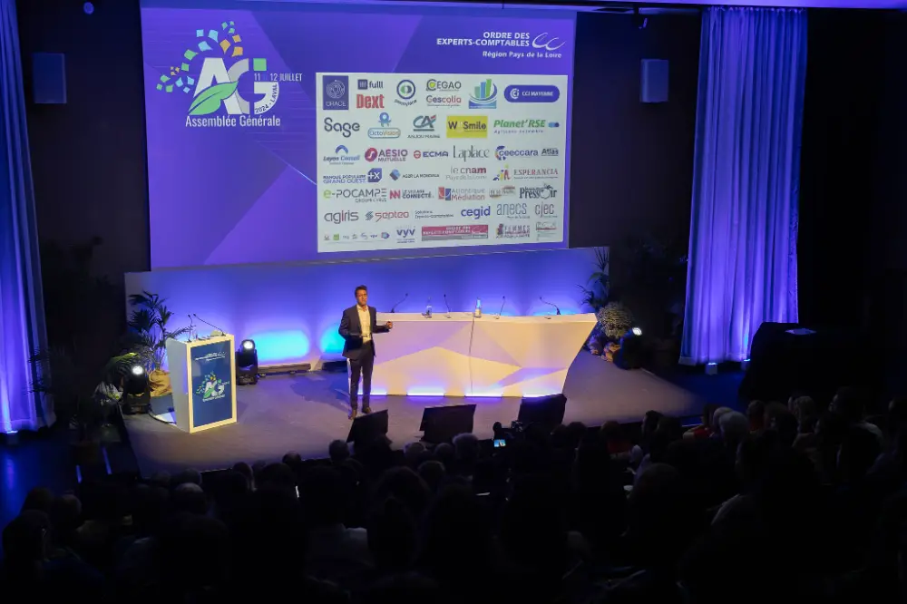 Conférence d’un intervenant sur scène lors d’une réunion professionnelle à Bruxelles avec partenaires et sponsors