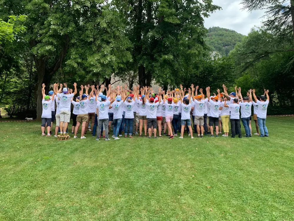Groupe de collaborateurs en plein team building en extérieur à Grenoble, bras levés en signe d’unité.