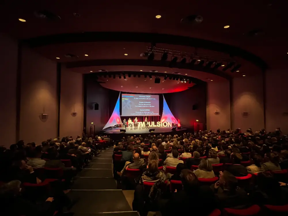 Conférence plénière dans une grande salle avec mise en scène lumineuse, organisée par une agence événementielle à Bruxelles.