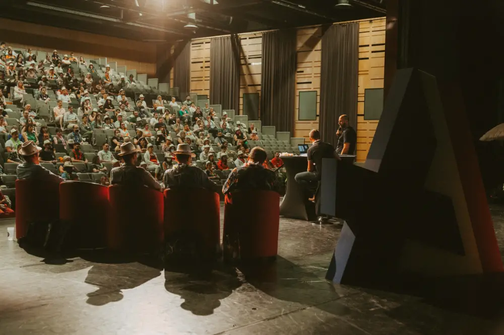 Conférence professionnelle à Grenoble avec une salle comble et un panel d’intervenants sur scène.