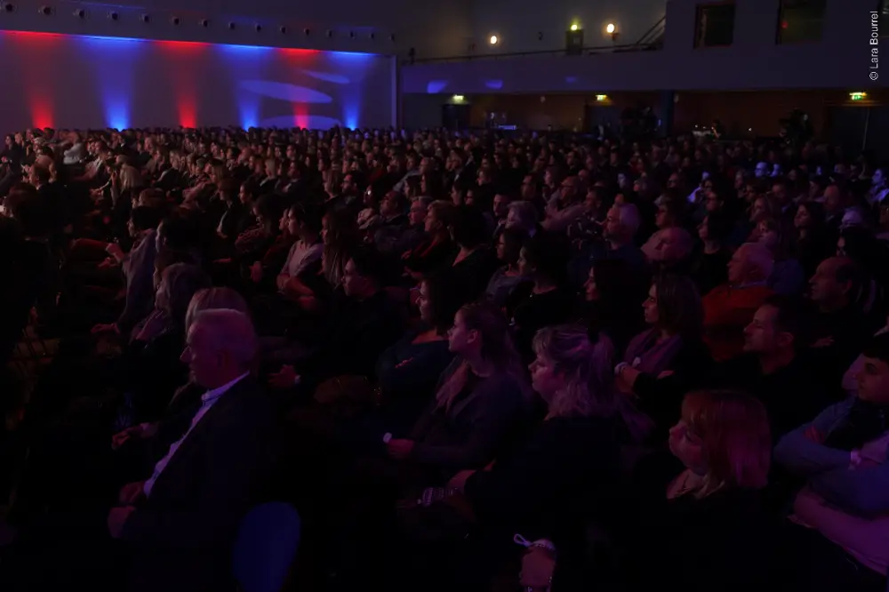 Public nombreux sous un éclairage bleu et rouge à une convention entreprise à Saint-Étienne