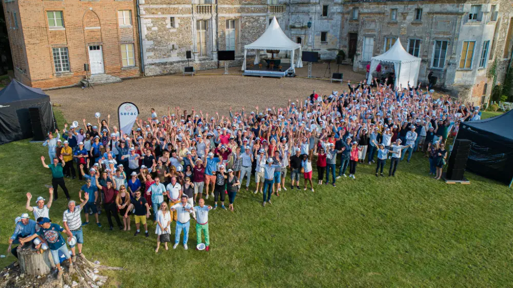 Photo de groupe lors d’une journée de cohésion au Mans avec levée de bras collective devant un château