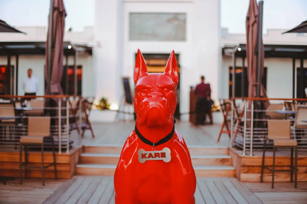Sculpture géante d’un chien rouge brandé KARE sur une terrasse de restaurant, utilisée comme élément visuel fort d’un événement corporate