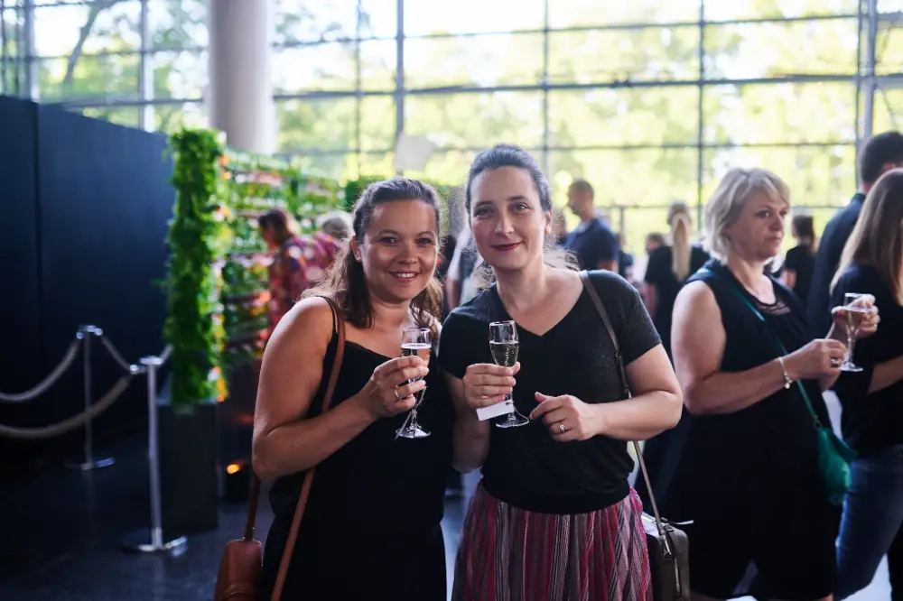 Deux collaboratrices souriantes tenant des verres de champagne pendant un événement professionnel à Reims