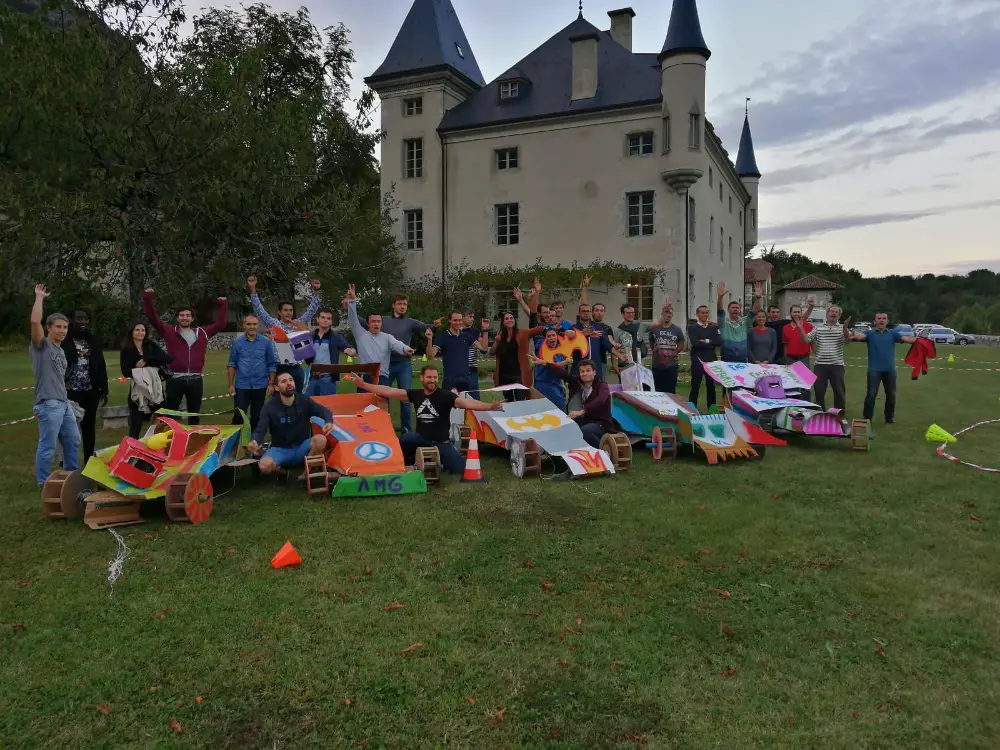 Activité ludique de construction de voitures en carton devant un château à Grenoble, dans le cadre d’un séminaire d’entreprise.