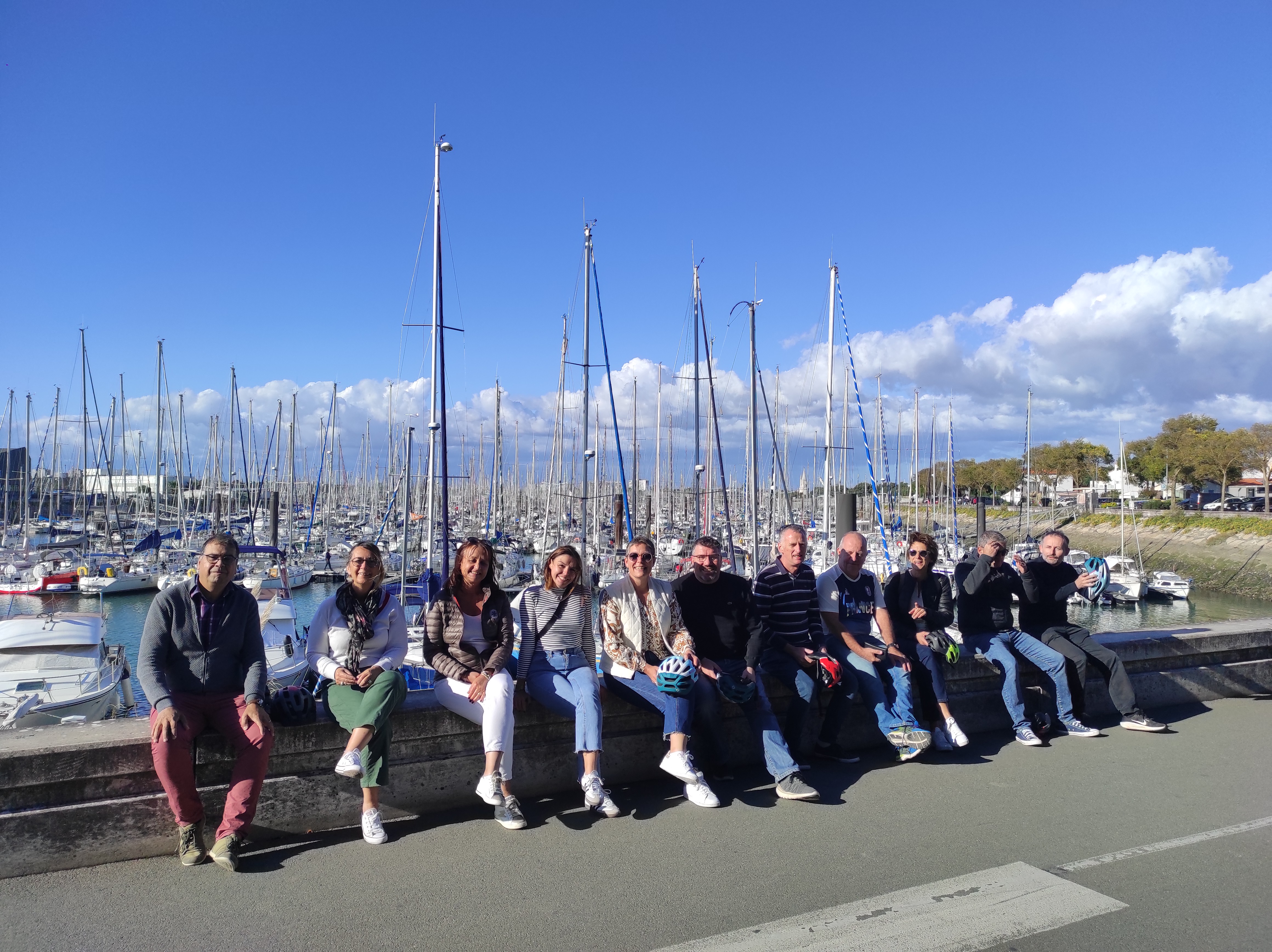 Groupe de collaborateurs en sortie après un séminaire, devant un port de plaisance