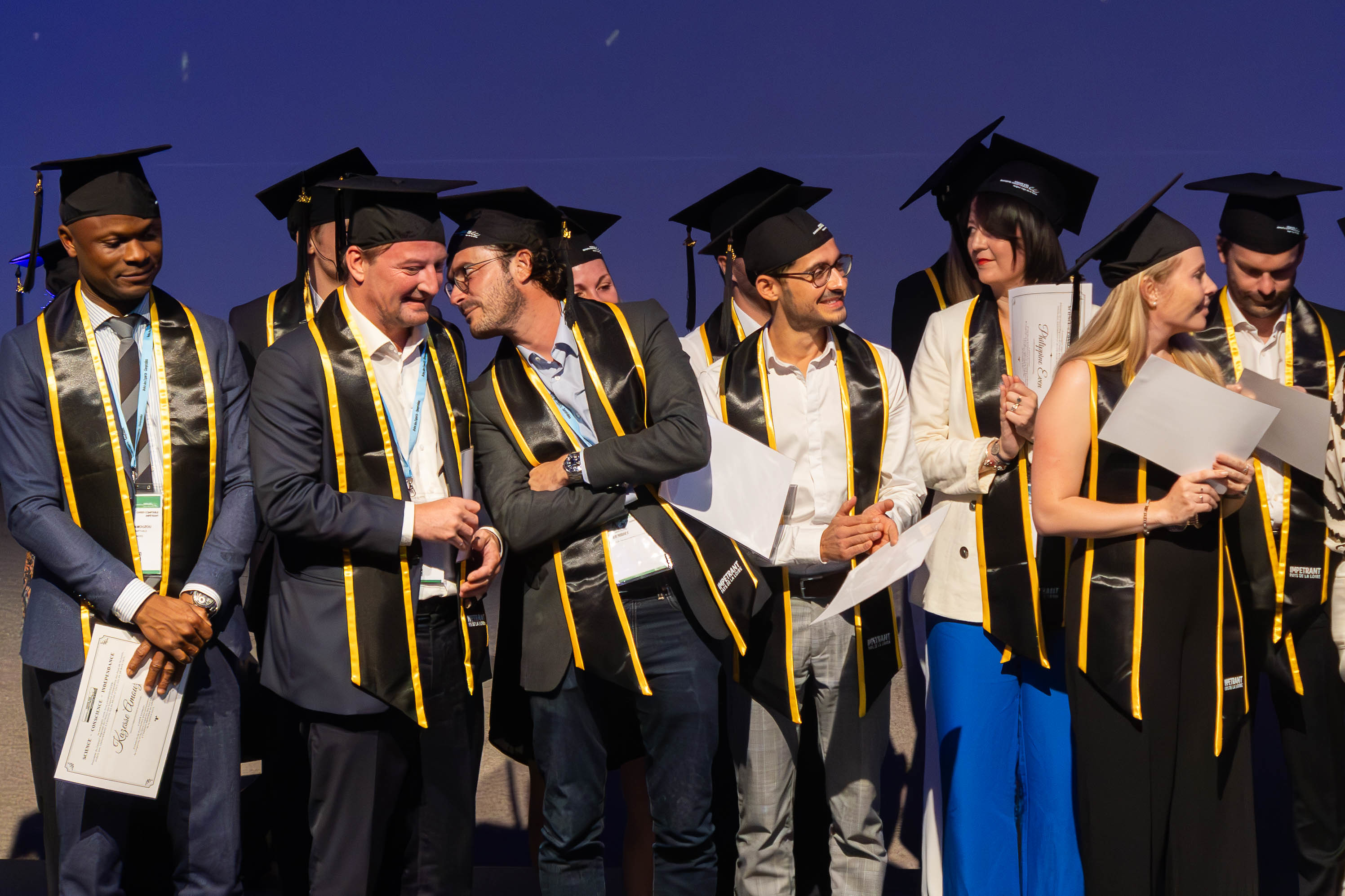 Délivrance des diplômes sur scène, diplômés portant la toque